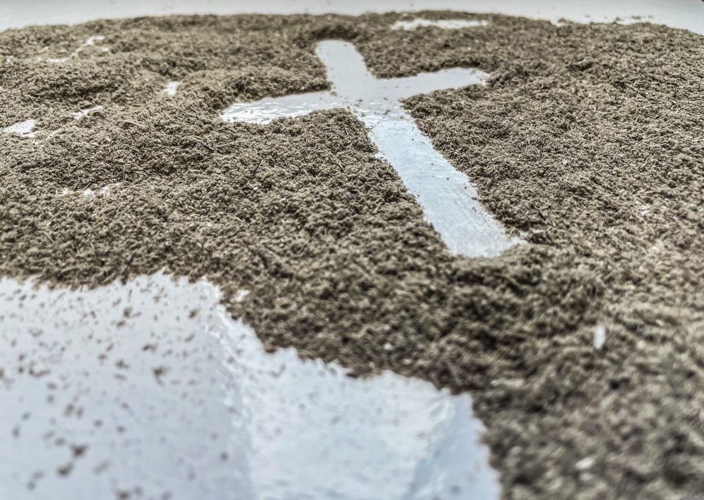 Bild, welches ein Kreuz zeigt, das in Asche gezeichent wurde